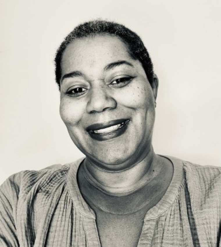 embedded counselor smiling to the camera against a plain wall. The image is in a toned black and white color.
